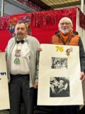 Wernes Karnevalisten Stan Overmann, Ludger Goers, Gottfried Forstmann und Georg Götz (von links) stehen in der Wagenbauhalle und halten Plakate und Fotos in Händen.