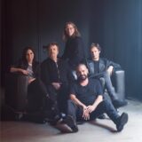 Die Band Alphaville sitzt auf einer schwarzen Couch
