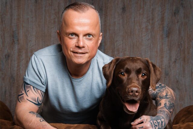 Thorsten „Toto“ Habel aus Dortmund und Assistenzhündin Hanni posieren in einem Fotostudio.
