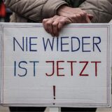 Ein Demonstrant hält ein Plakat mit der Aufschrift „Nie wieder ist jetzt“ (Archivbild).