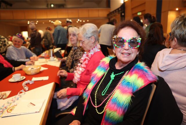 Eine ältere Frau mit bunter Brille und buntem Schmuck