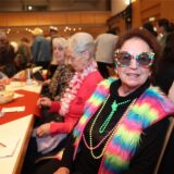 Eine ältere Frau mit bunter Brille und buntem Schmuck