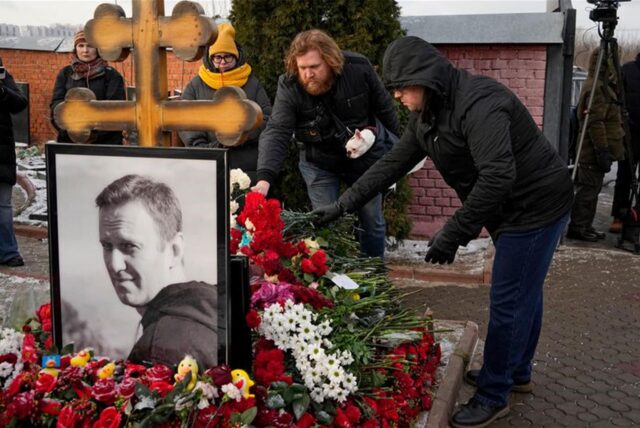 Menschen legen Blumen nieder.