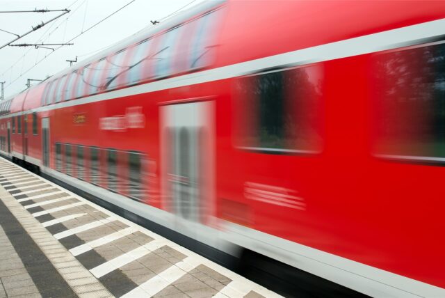 Ein roter Zug fährt durch einen Bahnhof.