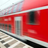 Ein roter Zug fährt durch einen Bahnhof.