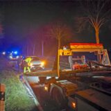 Ein Mitarbeiter eines Abschleppdienstes bereitet einen verunfallten Wagen für das Abschleppen vor, während ein zweiter Mann danebensteht.