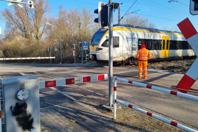 Auf der Bahnstrecke zwischen Werl und Unna steht am 18.2. ein Zug am Bahnübergang in Hemmerde. Ein Bahnmitarbeiter sichert den Bahnübergang ab.