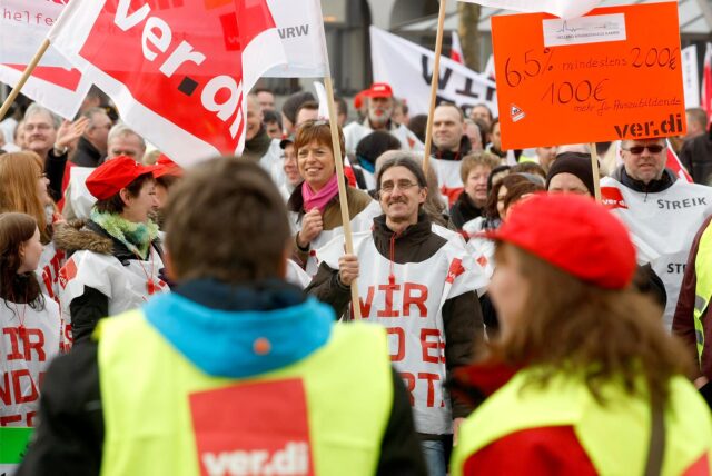 Menschen streiken mit Fahnen und Plakaten.