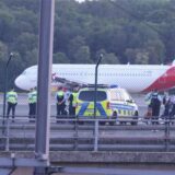 Sicherheitspersonal und Polizisten stehen auf dem Flugfeld und versuchen Aktivisten der Gruppe Letzte Generation vom Asphalt zu lösen, nachdem sie sich festgeklebt haben.