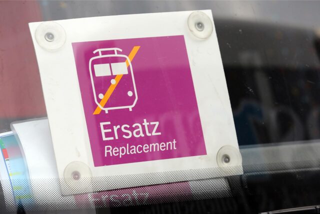 An einer Frontscheibe eines Busses hängt ein Schild, das ihn als Schienenersatzverkehr auszeichnet.
