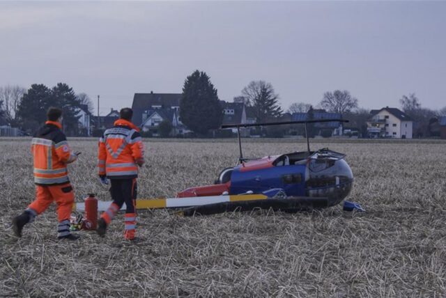 Einsatzkräfte gehen über ein Feld zu einem abgestürzten Kleinhubschrauber. Die zwei Insassen wurden bei dem Hubschrauberabsturz verletzt.