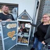 Philipp Bien (links) und Katja Lösch bieten in ihrem Bee-Kreate-Schrank seit Februar handgefertigte Geschenke und Mitbringsel an. Auf dem Bild stehen sie am Schrank. Katja Lösch hält einen Teller in der Hand.