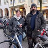 Eine Frau und ein Mann stehen hinter einem Fahrrad