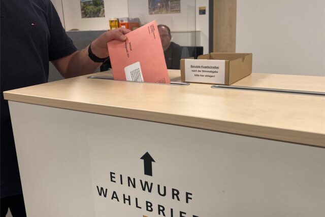 Ein Wahlbrief wird in eine Wahlurne eingeworfen.