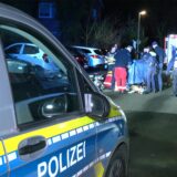 Rettungskräfte und Polizisten schirmen den Tatort mit einem Tuch ab. Im Vordergrund steht ein Polizeiwagen.