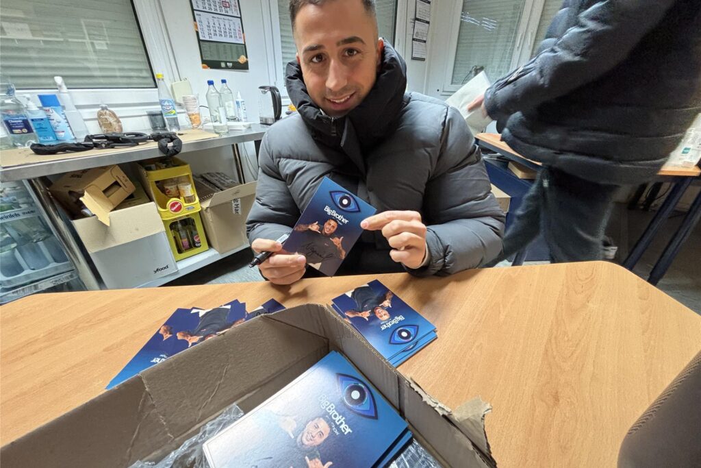 NAdiem Bahjat an einem Tisch mit seinen Autogrammkarten der Big Brother Show. NAdiem Bahjat an einem Tisch mit seinen Autogrammkarten der Big Brother Show.