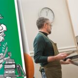 Mann schiebt Backblech in den Backofen.