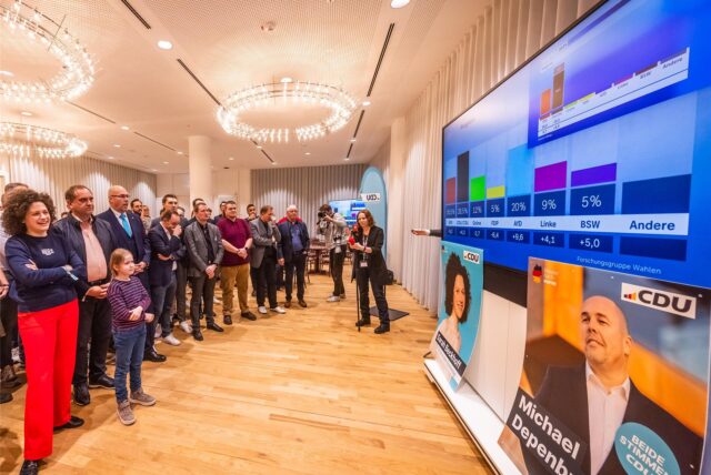 Im Rathaus in Dortmund beobachten Zuschauer Fernsehschirme mit Wahlergebnissen.