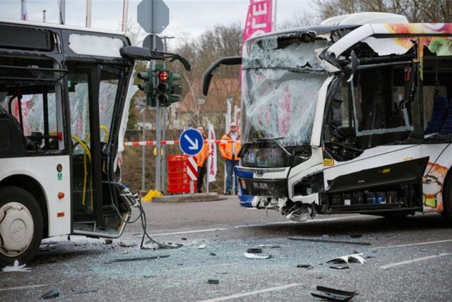 Polizisten stehen am Unfallort, nachdem zwei Linienbusse auf einer Kreuzung in Saarbrücken frontal zusammengestoßen sind.