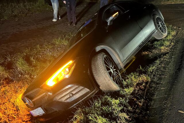 Ein schwarzer Mercedes liegt neben der Straße.