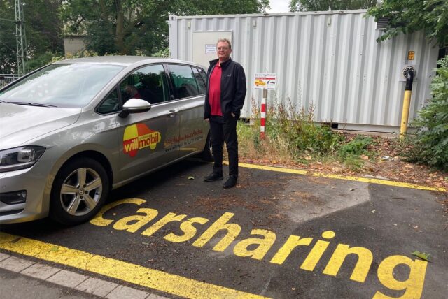 Carsharing-Betreiber Jochen Will steht auf einem Carsharing-Parkplatz in Dortmund neben einem Auto.