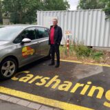 Carsharing-Betreiber Jochen Will steht auf einem Carsharing-Parkplatz in Dortmund neben einem Auto.