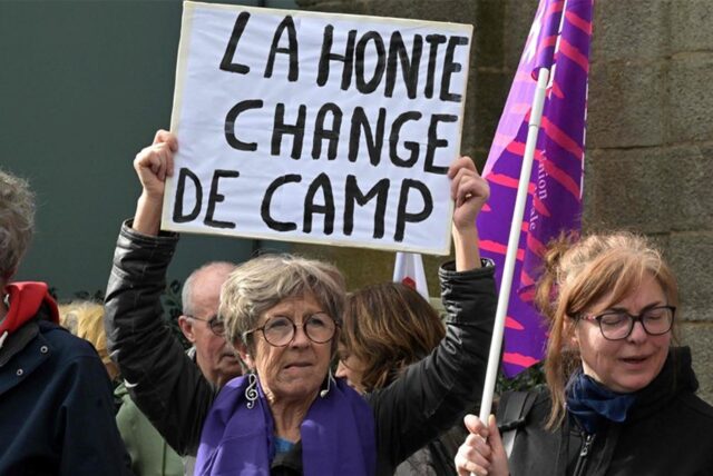 Eine Demonstrantin hält ein Schild mit der Aufschrift «La honte change de camp» (Die Scham wechselt die Seite) vor dem Gerichtsgebäude in Frankreich, in dem der Prozess gegen einen pensionierten Chirurgen beginnt.