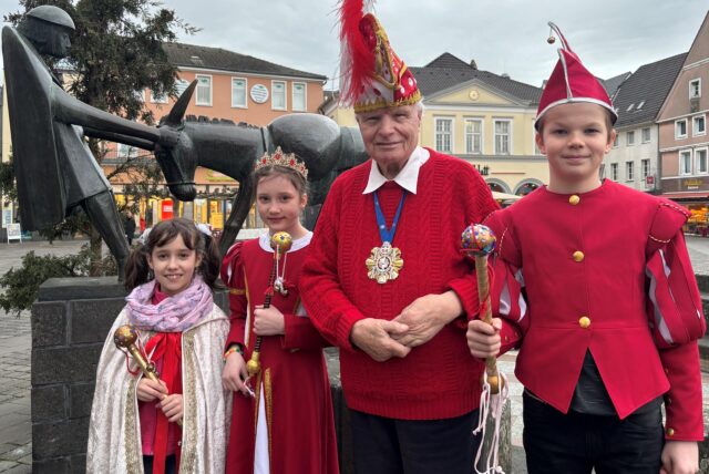 Der 90-jährige Karnevalist Helmut Scherer (M.) mit dem Kinderdreigestirn der Liedbachschule in Billmerich vor dem Eselsbrunnen auf dem Markt in Unna (von rechts nach links): Prinz Theo Lipkowski, Prinzessin Jette Chade und Antonia Koerdt von der Katharienschule, die für die erkrankte Präsidentin Nelly Kramer für das Foto eingesprungen ist.