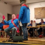 „Sup-Peiter“ bei der Nachbarschaft Westeneicken 2025: Die Männer in den blauen Oberteilen mit den roten Halstüchern verhandeln auf der Bühne des evangelischen Gemeindehauses in Schwerte-Westhofen.