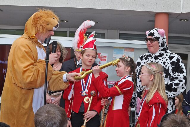 Auf dem Bild ist Bürgermeister Dirk Wiegand zu sehen, wie er den symbolisch den Schlüssel des Rathauses an das junge Prinzen-Kinderpaar übergibt.
