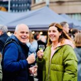 Zwei Gäste halten beim Feierabendmarkt in Dortmund ein Glas Wein in der Hand.