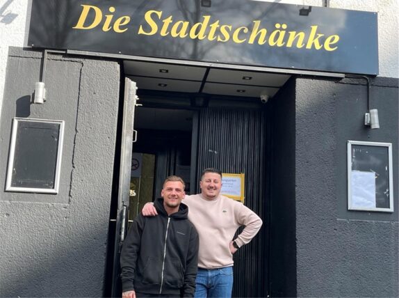 Zwei Männer stehen vor einer Kneipentür