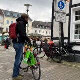 Ein Mann mit seinem Fahrrad an der Hand steht am Durchgang von der Gerhart-Hauptmann-Straße zum Alten Markt in Unna und blickt auf ein Schild, das den Beginn der Fußgängerzone markiert.