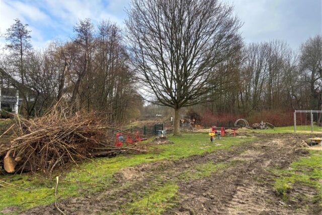 Abgesägte Bäume und abgebaute Spielgeräte liegen auf dem Spielplatz „Auf dem Hilf“ in Schwerte-Ergste. In der Wiese sind Spuren großer Baufahrzeuge zu sehen.