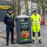 Ein Mitarbeiter vom Ordnungsamt und ein Mitarbeiter von der EDG stehen am Signal-Iduna-Park in Dortmund neben einem Glasmülleimer.