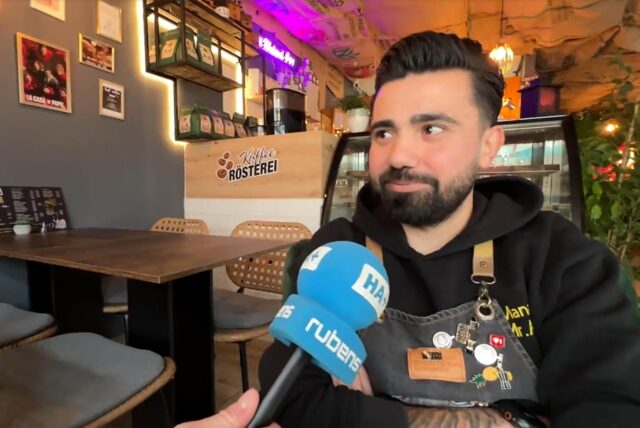 Der Inhaber des neuen Cafés in Unna spricht in ein Mikrofon.