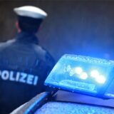 Ein Polizist steht neben einem Streifenwagen.