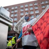 Ein Mann steht mit einer Fahne von Verdi vor dem Eingang des Klinikums Dortmund. Er trägt eine Plastikweste der Gewerkschaft Verdi, die zum Streik aufgerufen hat.