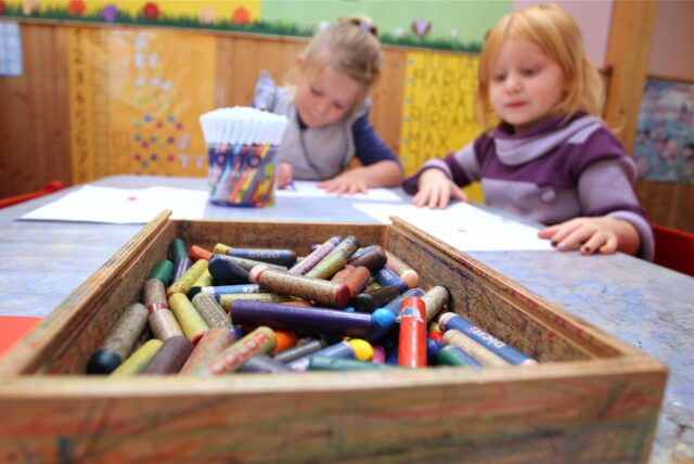 Kinder sitzen an einem Tisch und malen