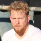 Robin Pfahl (in Weiß) sitzt auf der Auswechselbank.