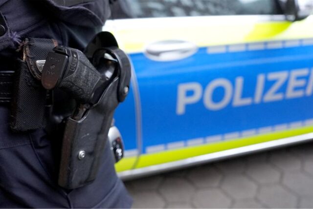 Ein Polizist steht vor einem Einsatzfahrzeug der Polizei.