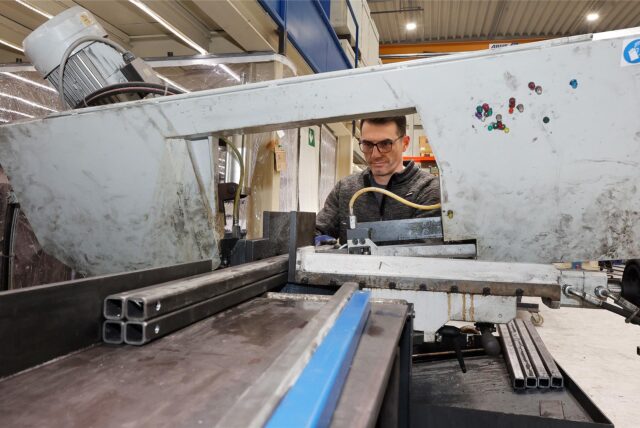 Fleurat Vula, Mitarbeiter der Firma Sabura, sägt mit einer stationären Metallsäge Vierkantrohre ab.