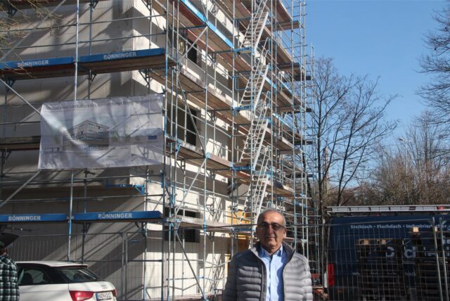 Kenan  Küçük steht vor dem Rohbau