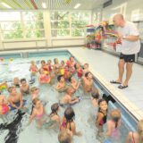 Im Becken des Massener Hellweg-Schwimmbades lauscht eine Schulklasse den Ausführungen ihres Lehrers Matthias Landsberg, der vom Beckenrand aus spricht.