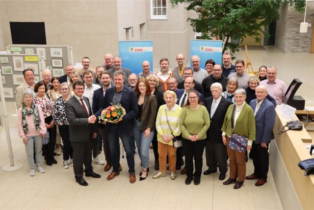 Der CDU-Ortsverbandsvorsitzende Frank Lausmann gratuliert Bernd Kasischke zur Bürgermeisterkandidatur. Um die beiden stehen im Foyer des Holzwickeder Rathauses zahlreiche CDU-Mitglieder aus der Gemeinde.