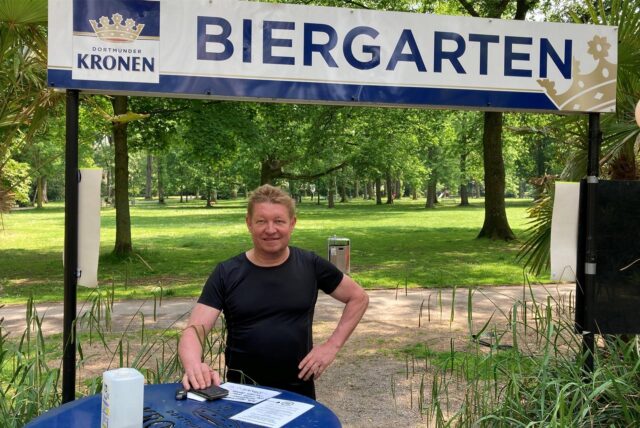 Klaus Erdmann steht vor einem Schild, auf dem „Biergarten“ zu lesen ist.