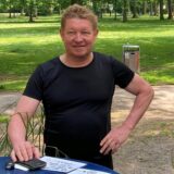 Klaus Erdmann steht vor einem Schild, auf dem „Biergarten“ zu lesen ist.