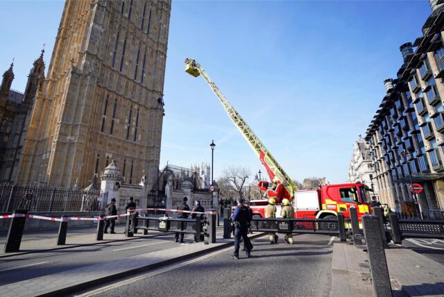 Feuerwehrleute nähern sich mit einem Korb einem Mann, der mit einer Palästina-Flagge auf einem Mauervorsprung des Elizabeth Towers, in dem sich die Glocke Big Ben am Palace of Westminster befindet, sitzt.