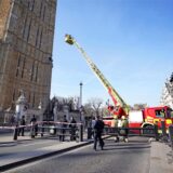 Feuerwehrleute nähern sich mit einem Korb einem Mann, der mit einer Palästina-Flagge auf einem Mauervorsprung des Elizabeth Towers, in dem sich die Glocke Big Ben am Palace of Westminster befindet, sitzt.