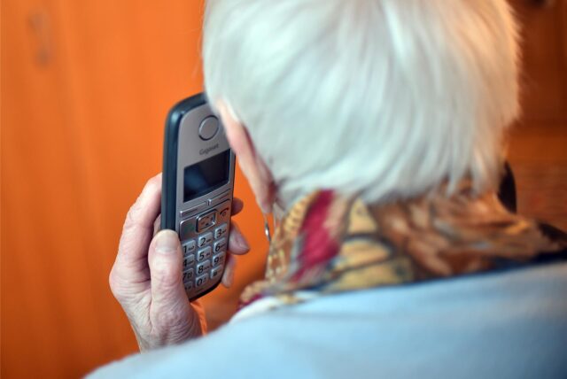 Eine ältere Frau hält ein Telefon an ihr Ohr.